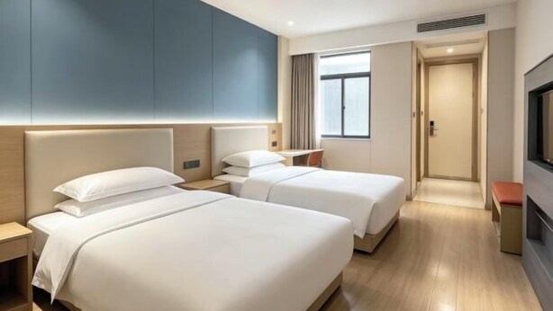 Une chambre d’hôtel avec deux lits, une télévision, un bureau et une fenêtre.