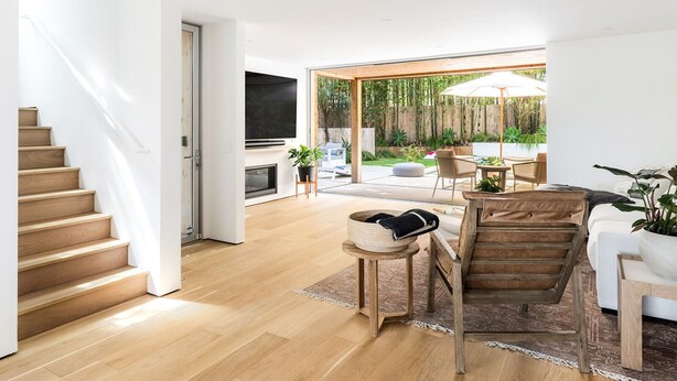 A modern living room with a staircase, a fireplace, and a view of the backyard.