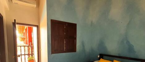 Een slaapkamer met een bed, een plafondventilator, een houten deur en een raam.