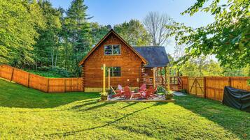 A wooden cabin with a deck and outdoor seating area.