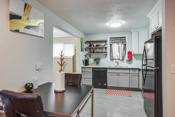 A modern kitchen with white cabinets, a black refrigerator, and a dining table with chairs. - 3 Mi to Dtwn Tacoma: Pet-Friendly Home (Tacoma)