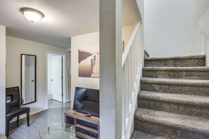 A modern interior with a staircase, a flat-screen TV, and a glass table.