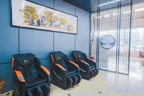 A waiting area with massage chairs, a framed artwork, and a view through a window. - Pizhou Dihao Jingzhi Hotel (Pizhou)