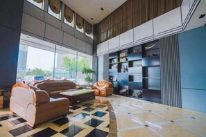 Un vestíbulo moderno con piso a cuadros, zona de estar con sofás y un amplio ventanal con vistas al exterior.