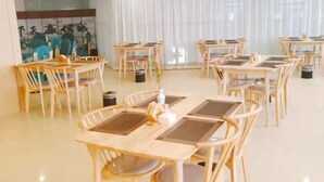 A dining area with wooden tables and chairs, a large window with sheer curtains, and a wall with a mural. - Pizhou Dihao Jingzhi Hotel (Pizhou)