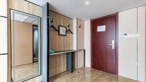A modern hallway with a wooden panel wall, a mirror, a door with a sign, and a small shelf. - Pizhou Dihao Jingzhi Hotel (Pizhou)
