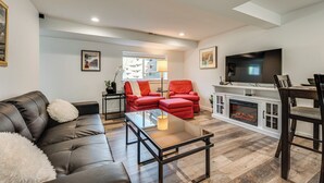 A modern living room with a leather sofa, red chairs, a glass coffee table, and a fireplace. - 14 Mi to Pearl Street Mall: Erie Getaway (Erie)
