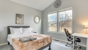 Un dormitorio con cama, escritorio y ventana.