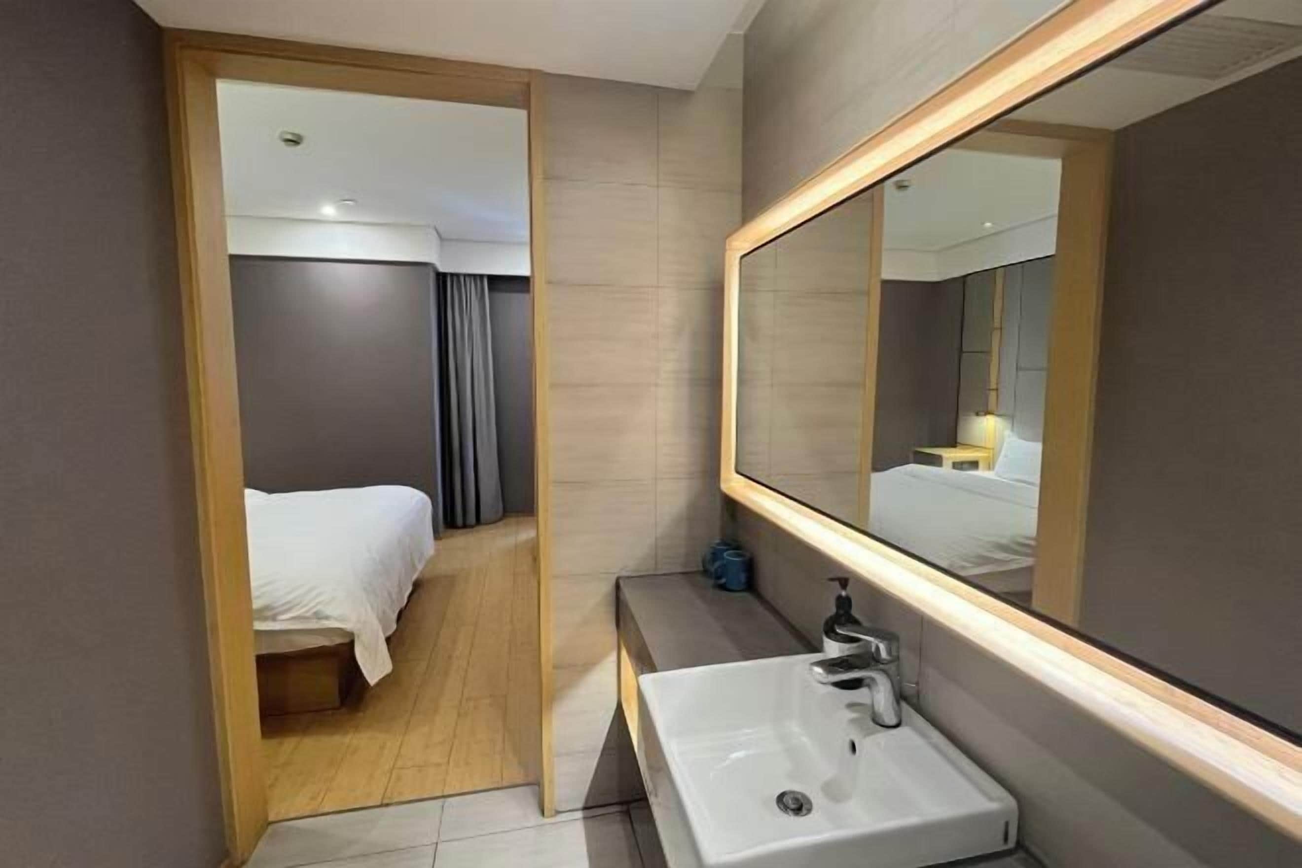 Un baño de hotel moderno con un espejo grande, un lavamanos y una zona de ducha.