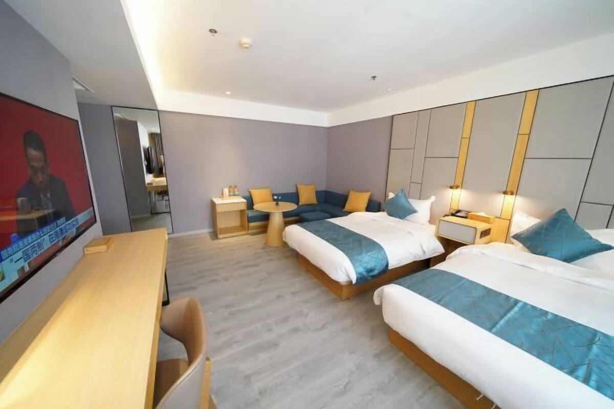 Ein Hotelzimmer mit zwei Betten, einem Schreibtisch, einem Sessel und einem Fernseher.