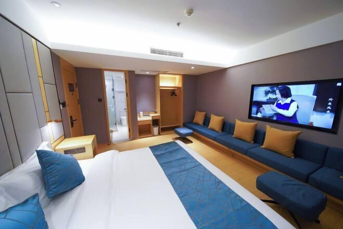 Ein Hotelzimmer mit einem großen Bett, einem Fernseher, einer Couch und einem kleinen Schreibtisch.
