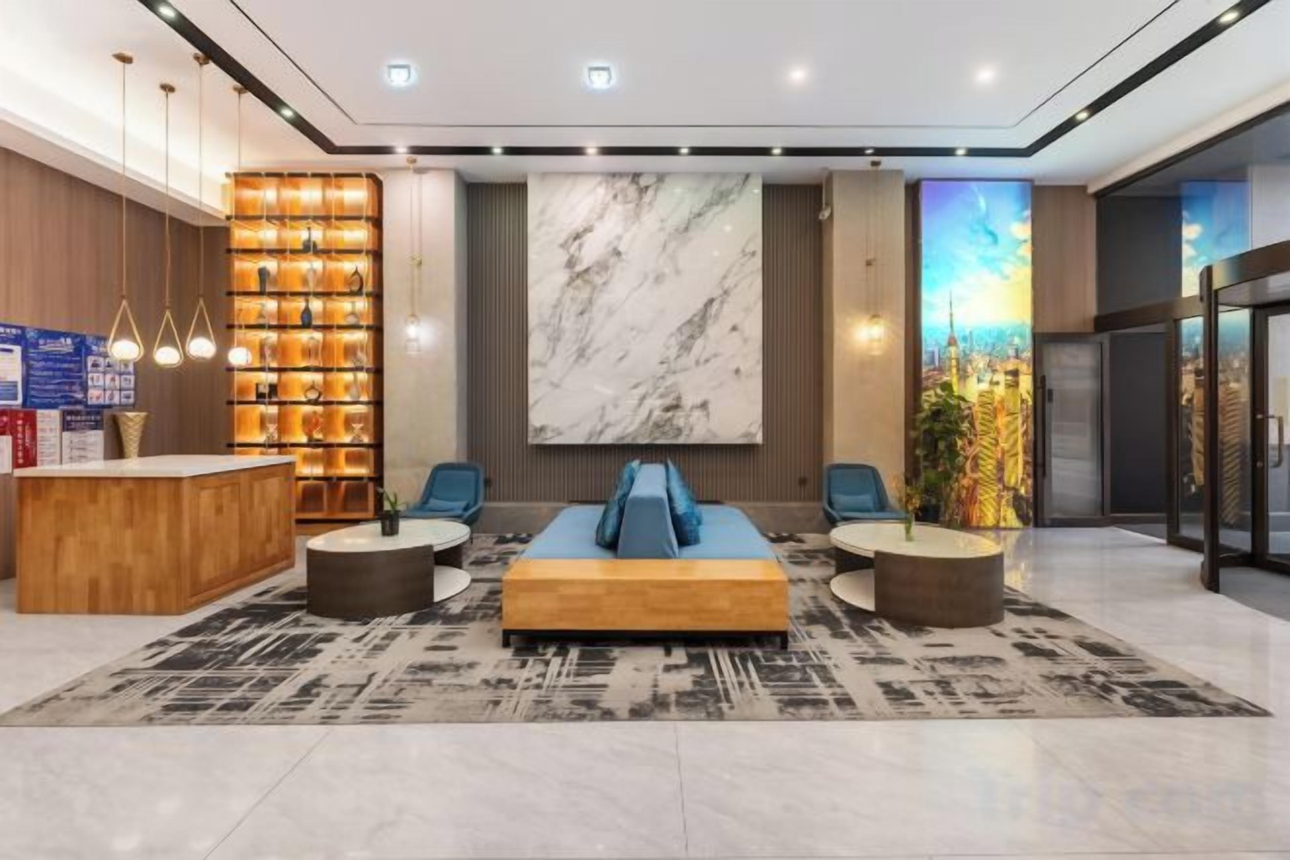 A hotel lobby with a reception desk, seating area, and a large cityscape mural.
