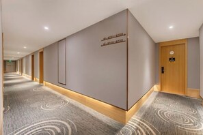 A hotel hallway with directional signs, a wooden door, and patterned carpet.