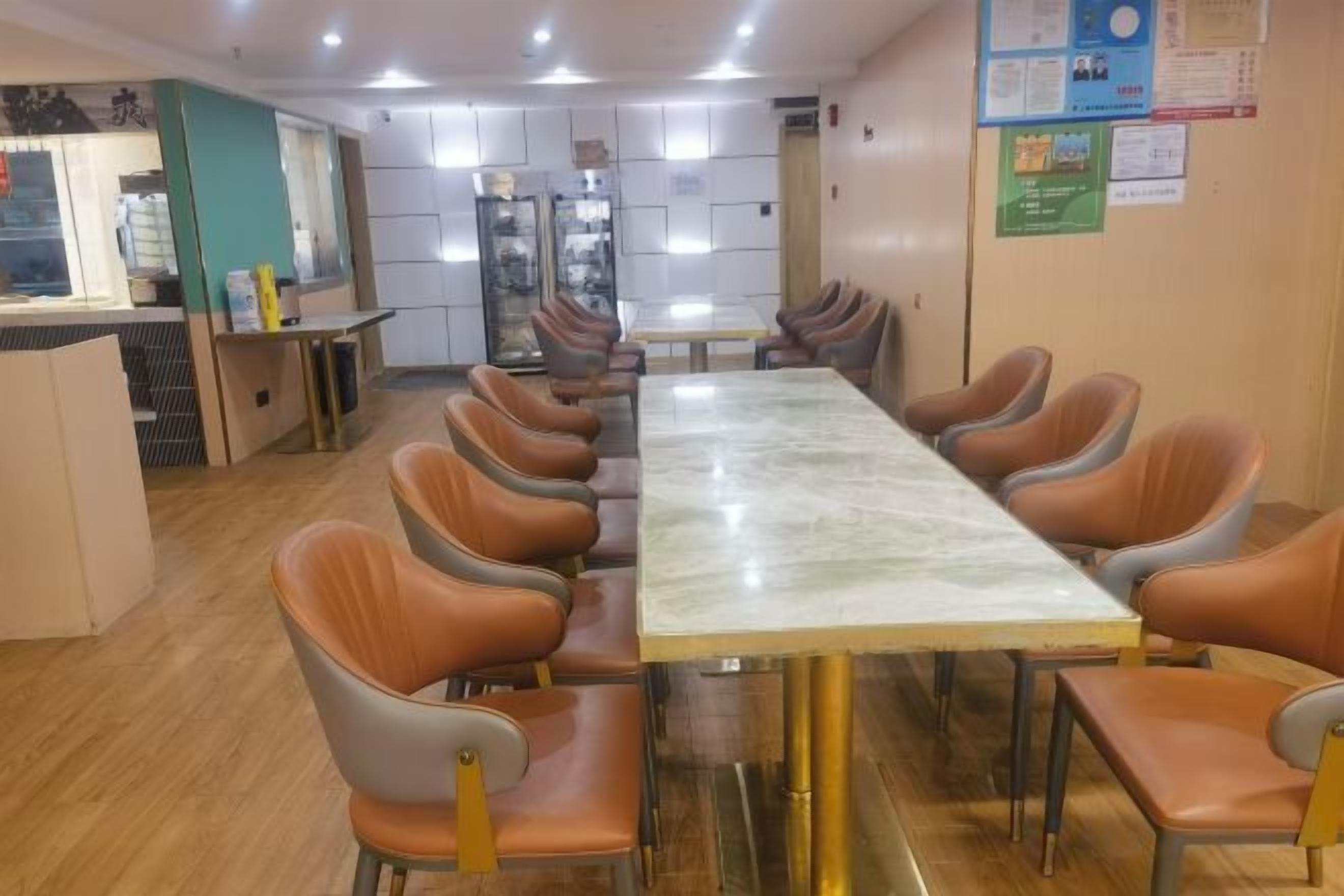 Sala de conferências com uma mesa grande e várias cadeiras, área de kitchenette e um quadro de avisos.