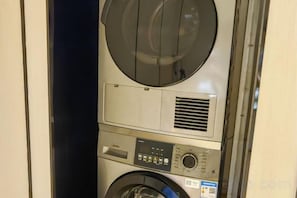 A compact, modern washing machine with a control panel and a circular drum, likely part of a hotel room's amenities. - Shanghai Huaihai Hotel (Shanghai)