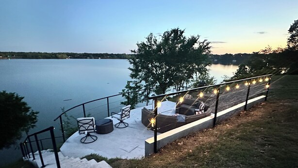 Une terrasse au bord de l’eau, dotée de sièges extérieurs, d’une rambarde et de guirlandes lumineuses.