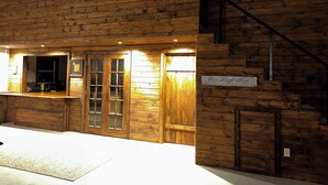 Une cabane en bois avec un coin bar, un escalier et une pancarte sur laquelle on peut lire : « Vivez. Riez. Aimez. »