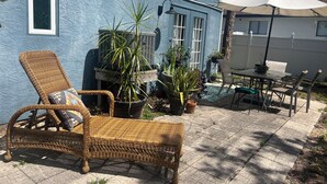 A patio with wicker furniture, potted plants, and a table with chairs. - King Studio Explore SWFL Beach, Trails & Treasures (Fort Myers)