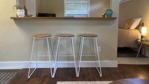 A kitchen with a wooden countertop, three white bar stools, a ceiling fan, and a window with blinds. - King Studio Explore SWFL Beach, Trails & Treasures (Fort Myers)