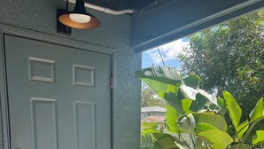 A grey door with a keyhole, a black doormat, and potted plants outside. - King Studio Explore SWFL Beach, Trails & Treasures (Fort Myers)