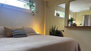A bedroom with a bed, pillows, a bedside table, a mirror, and potted plants. - King Studio Explore SWFL Beach, Trails & Treasures (Fort Myers)