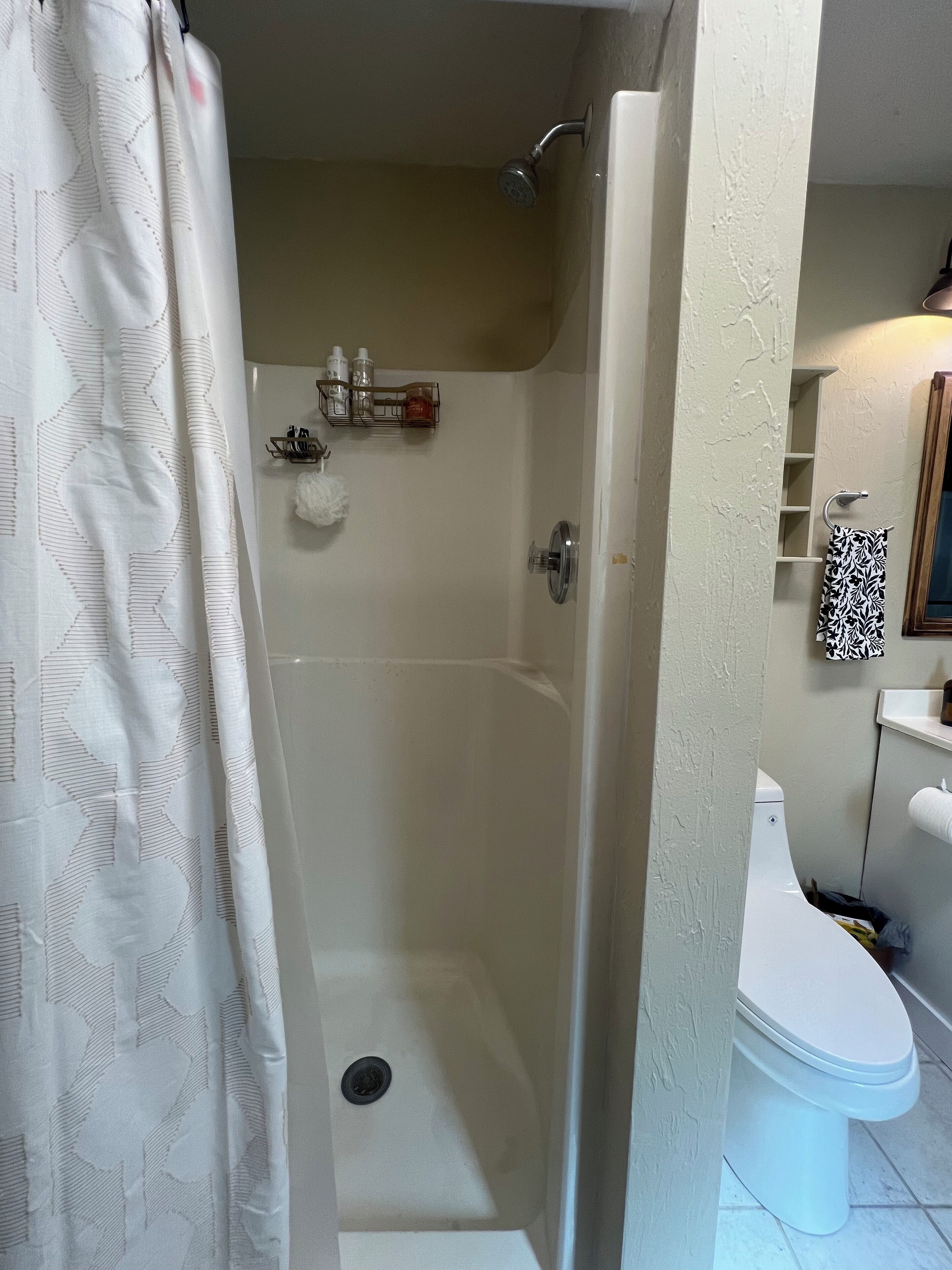 A bathroom with a shower, toilet, and a towel rack.