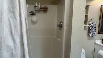 A bathroom with a shower, toilet, and a towel rack.