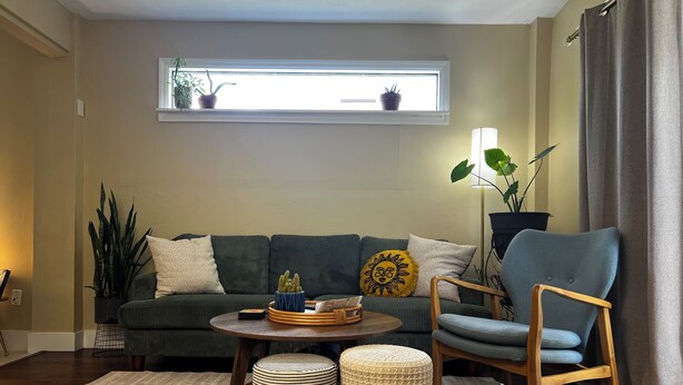 A living room with a sofa, a chair, a coffee table, and a window with plants. - King Studio Explore SWFL Beach, Trails & Treasures (Fort Myers)