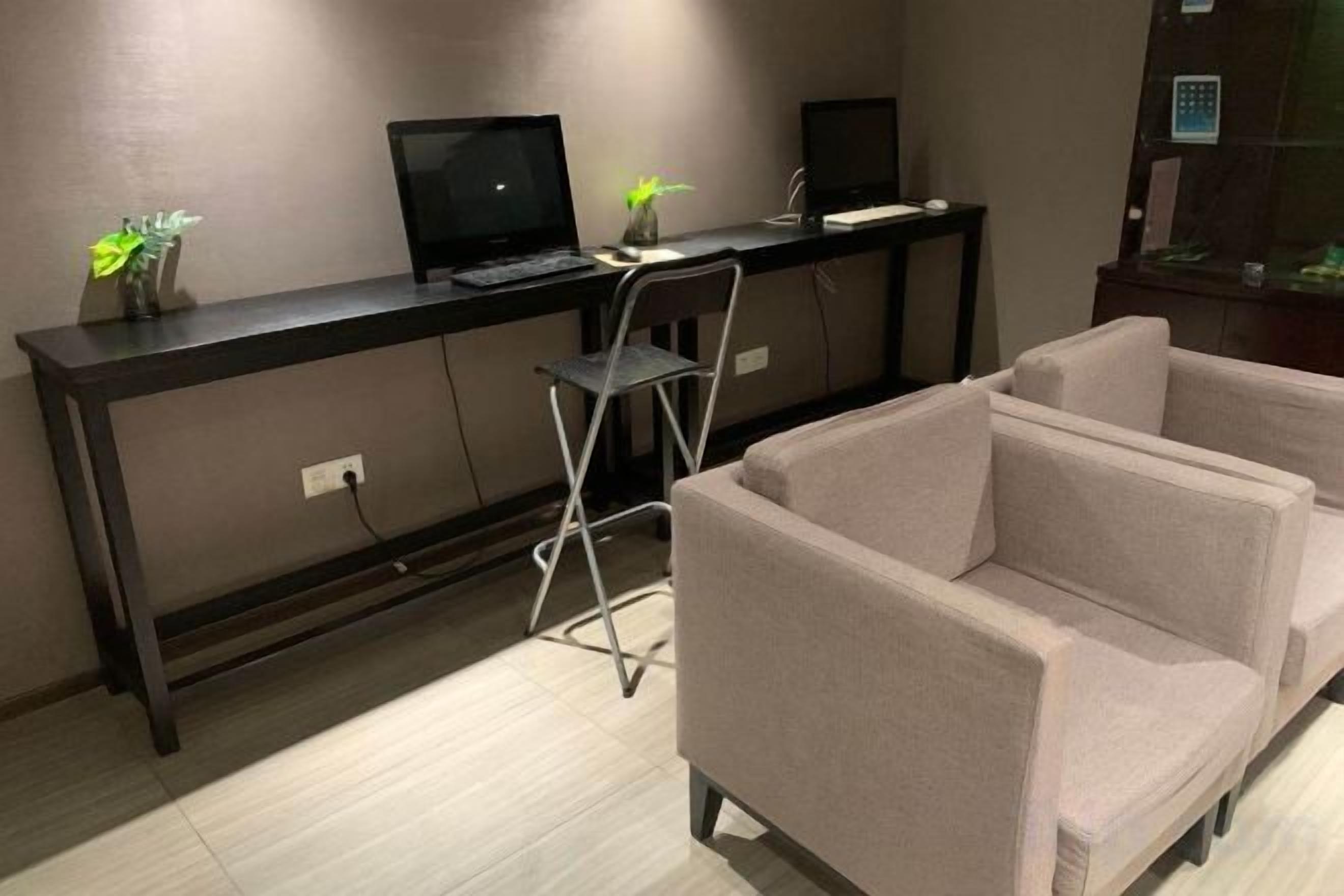A room with a desk, two chairs, a sofa, and a small table with decorative items.