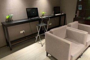 Ett rum med ett skrivbord, två stolar, en soffa och ett litet bord med dekorativa föremål.