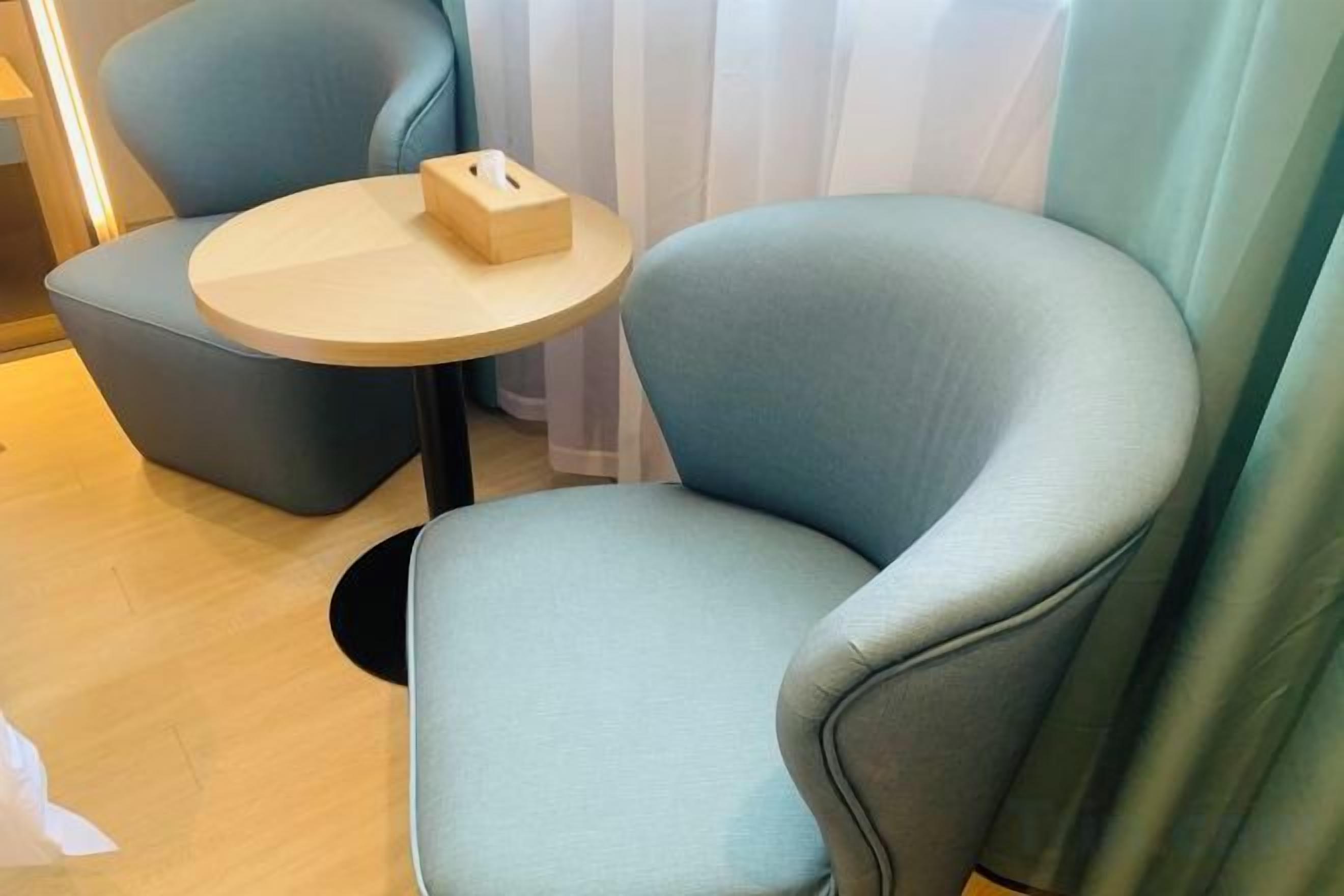 A room with a light blue armchair and a small round table with a box on it.