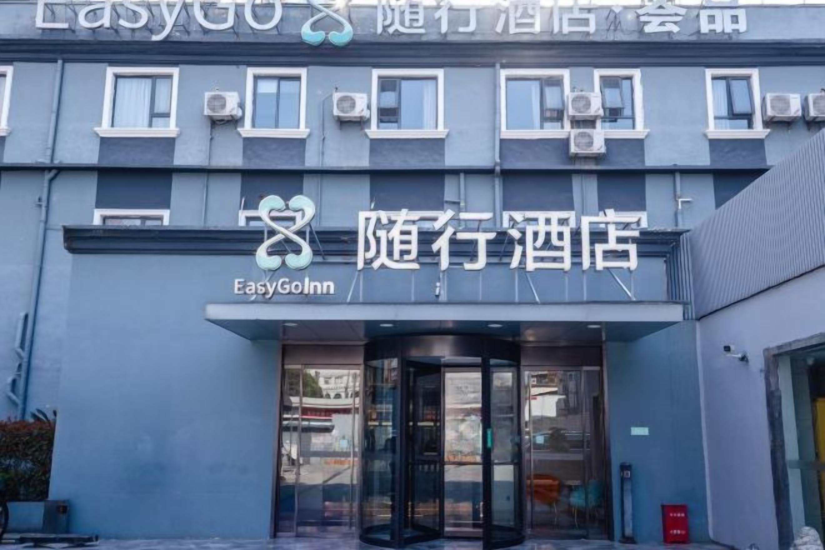 Entrada de un hotel con puerta de cristal y un letrero que dice 'EasyGoInn'.