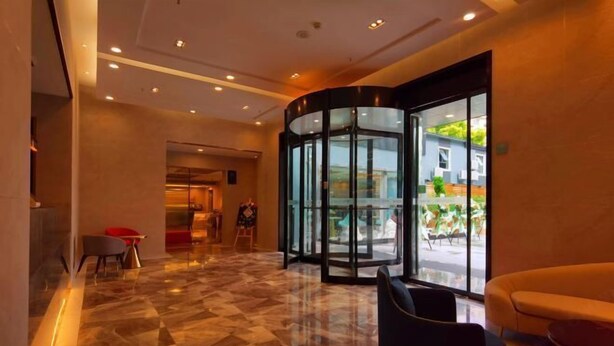 A lobby with a marble floor, a revolving door, and a seating area with a sofa and chairs. - Accompanying Hotel·Yipin (Shanghai Lujiazui Financial and Trade Zone) (Shanghai)