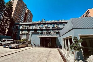 A hotel with a modern facade, multiple floors, and a parking area in front. - Accompanying Hotel·Yipin (Shanghai Lujiazui Financial and Trade Zone) (Shanghai)