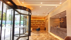 A modern reception area with a glass revolving door, a reception desk, and a seating area with a marble floor. - Accompanying Hotel·Yipin (Shanghai Lujiazui Financial and Trade Zone) (Shanghai)
