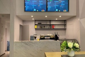 A modern reception area with a marble counter, a coffee machine, and a menu display. - Accompanying Hotel·Yipin (Shanghai Lujiazui Financial and Trade Zone) (Shanghai)