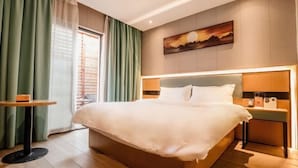 A modern hotel room with a large bed, a bedside table, a nightstand, and a painting on the wall. - Accompanying Hotel·Yipin (Shanghai Lujiazui Financial and Trade Zone) (Shanghai)