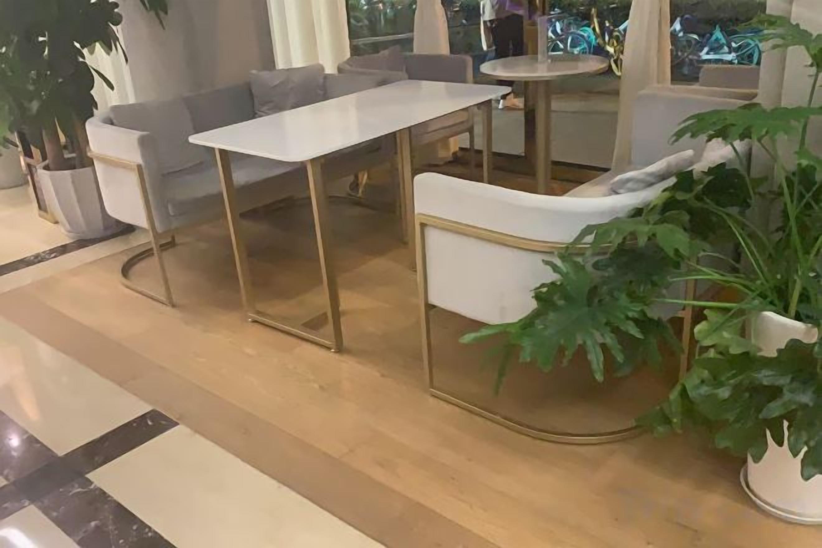 A modern interior with a white sofa, a white table, and a potted plant.