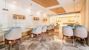 A modern dining area with marble flooring, white and blue chairs, and wooden ceiling panels. - Accompanying Hotel·Yipin (Shanghai Lujiazui Financial and Trade Zone) (Shanghai)