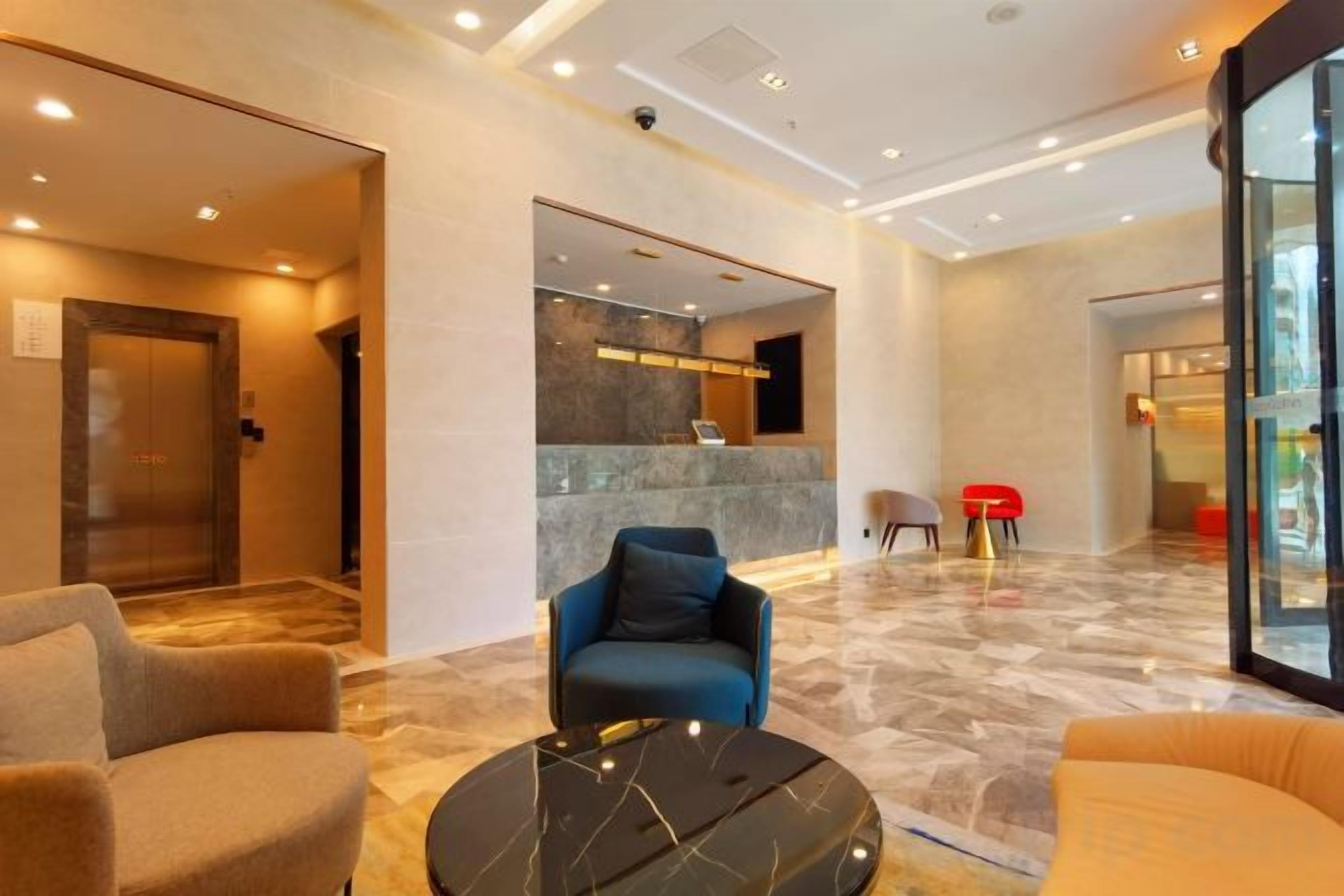 A hotel lobby with seating areas, a reception desk, and a glass partition.