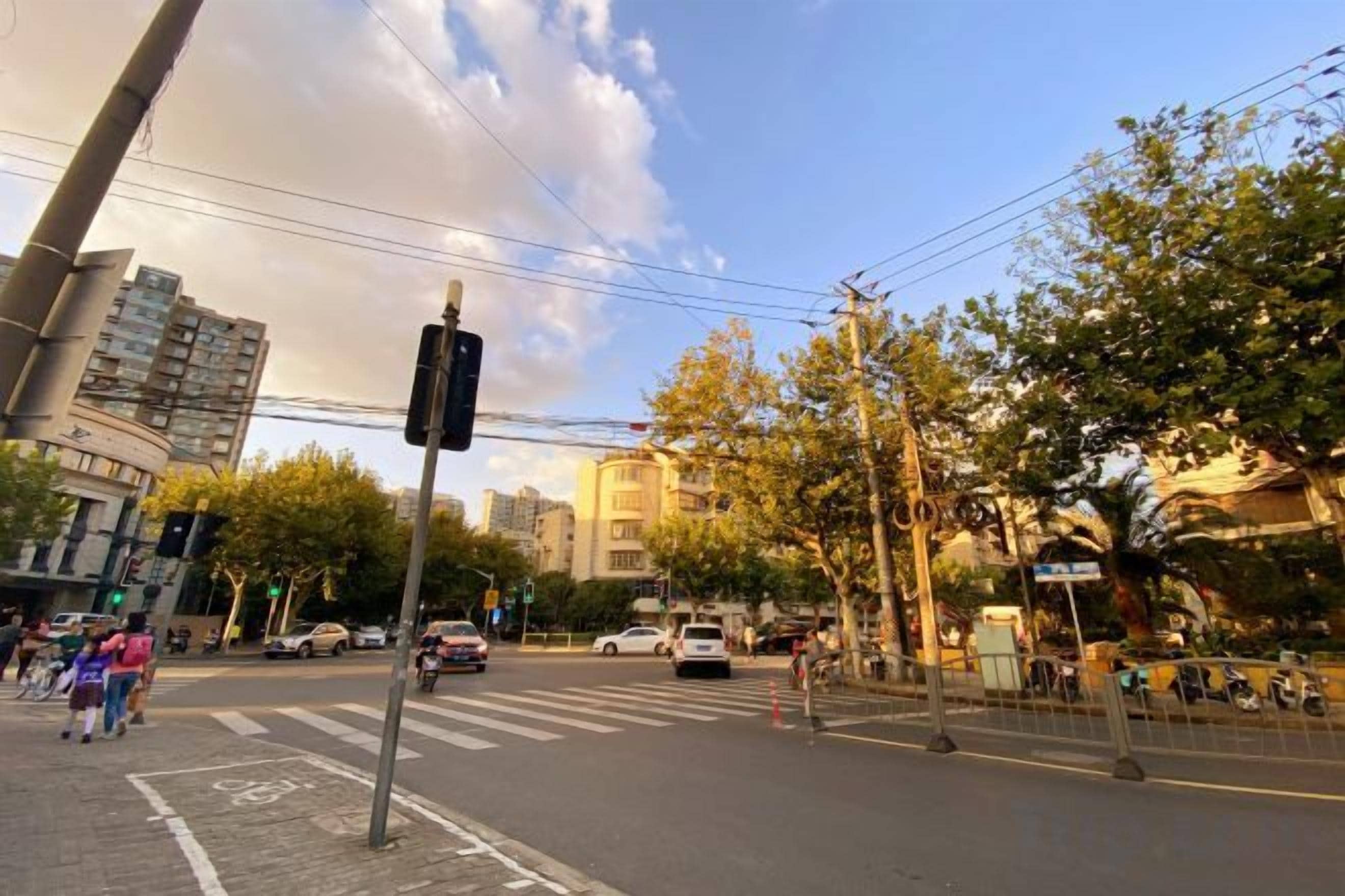 A street intersection with traffic lights, vehicles, and pedestrians.