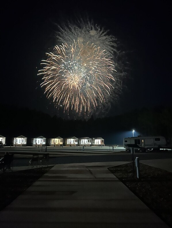 A nighttime scene with a large firework display over a row of small, uniformly lit houses. - Tiny Homes for Rent, minutes to the Casino, Golf Course & Water Park (Philadelphia)