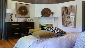Un dormitorio con cama, cómoda, chimenea y obras de arte en las paredes.