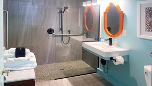 Un baño moderno con ducha, lavamanos con espejo y retrete.