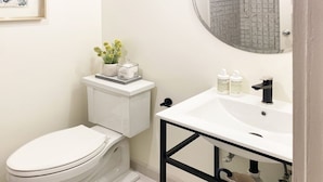 Ein modernes Badezimmer mit einer weißen Toilette, einem runden Spiegel und einem weißen Waschbecken mit schwarzen Rahmen.