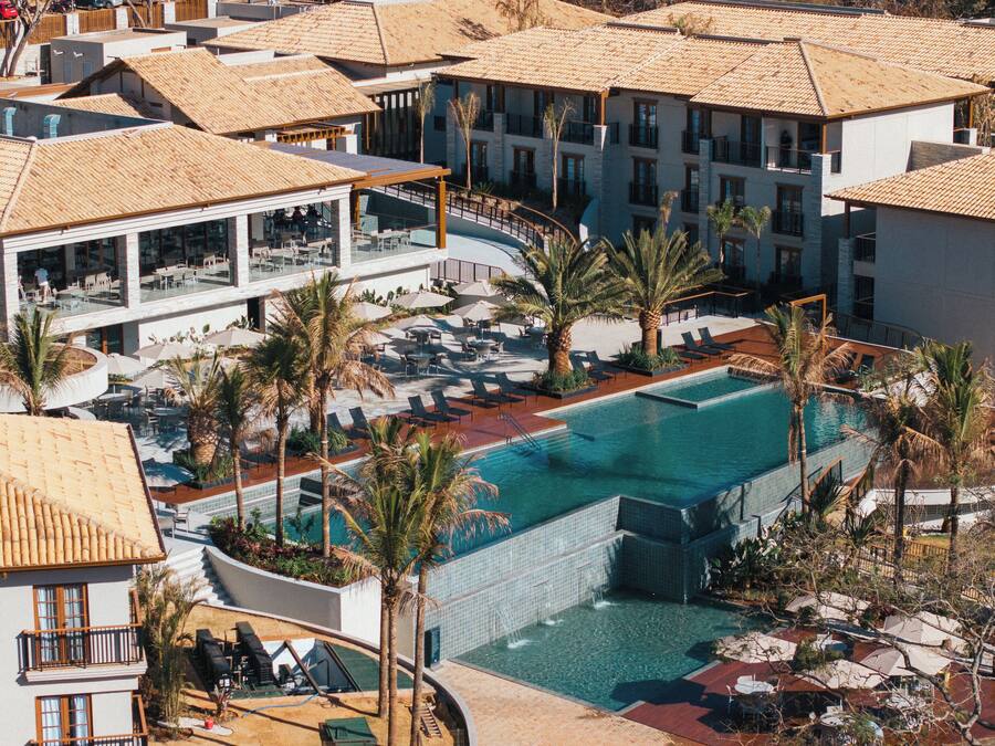 A resort with a central swimming pool, multiple lounge areas, and a variety of outdoor seating arrangements.