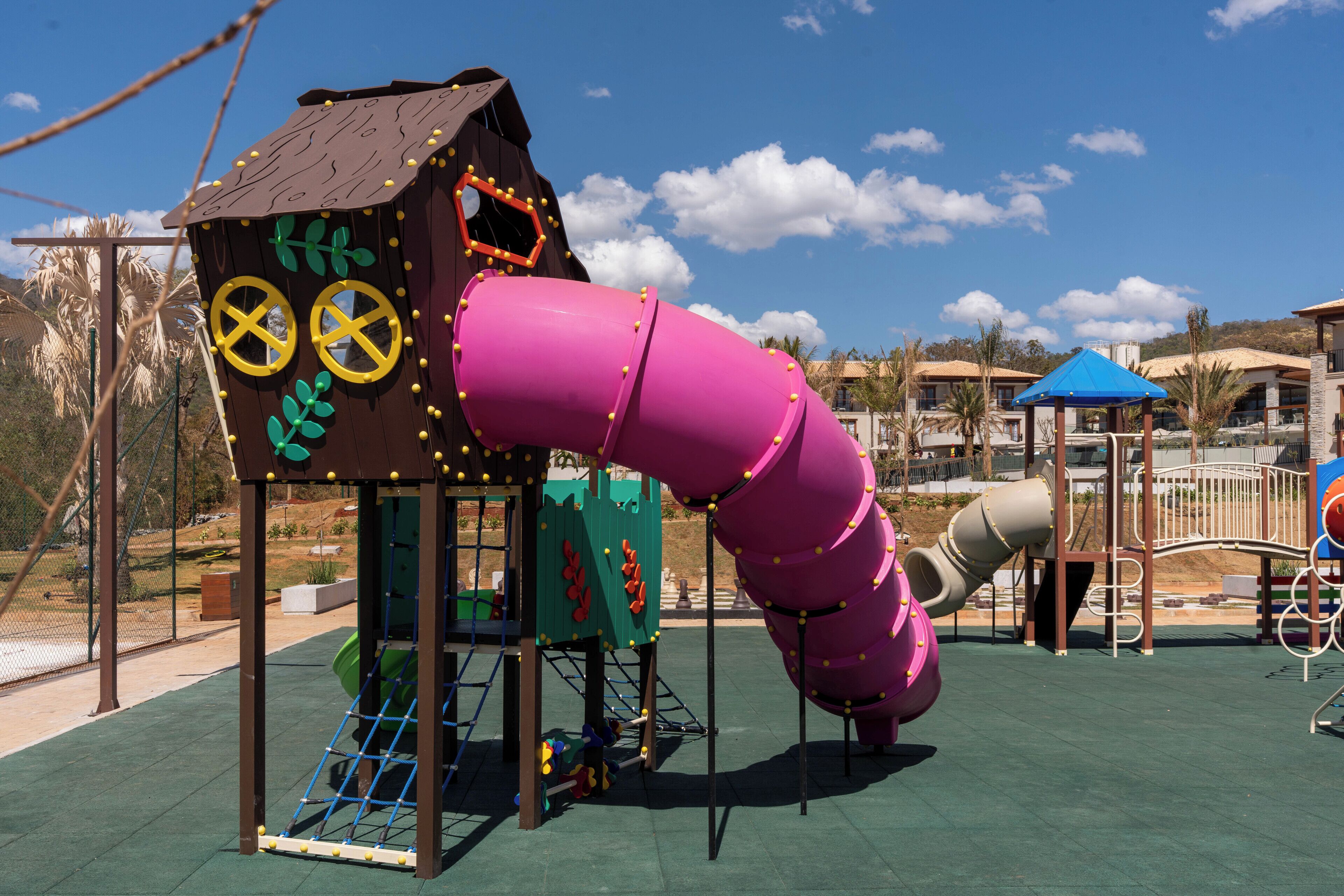 A playground with a slide, climbing structures, and a playhouse.