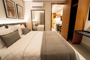 Une chambre d’hôtel avec un grand lit, une armoire en bois, un bureau et un miroir.