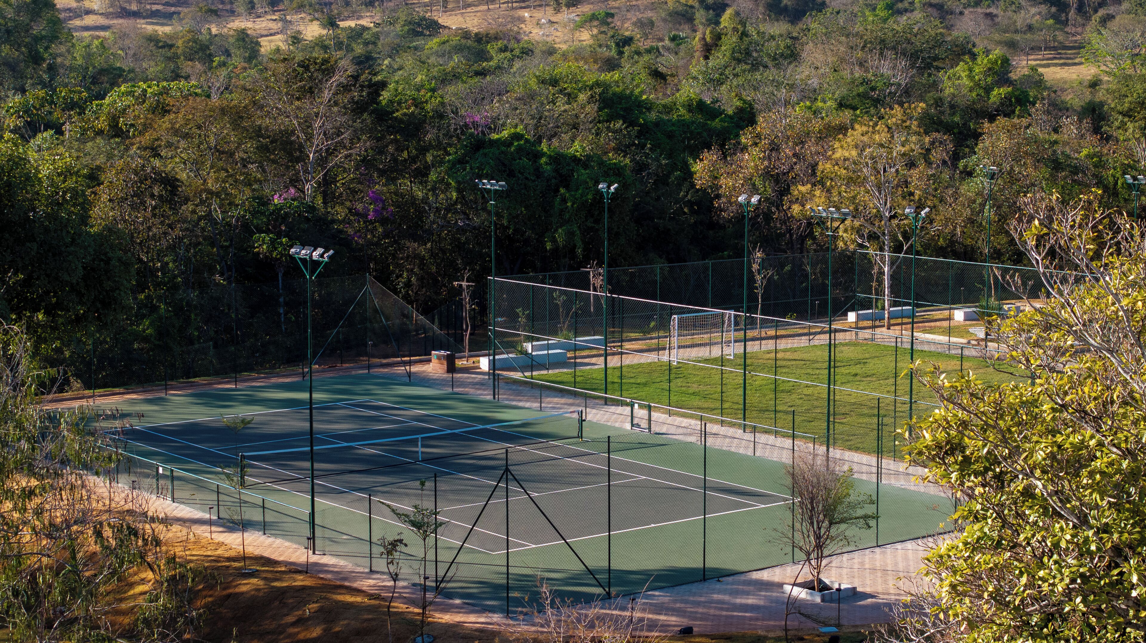 Una cancha de tenis rodeada de árboles y una valla.