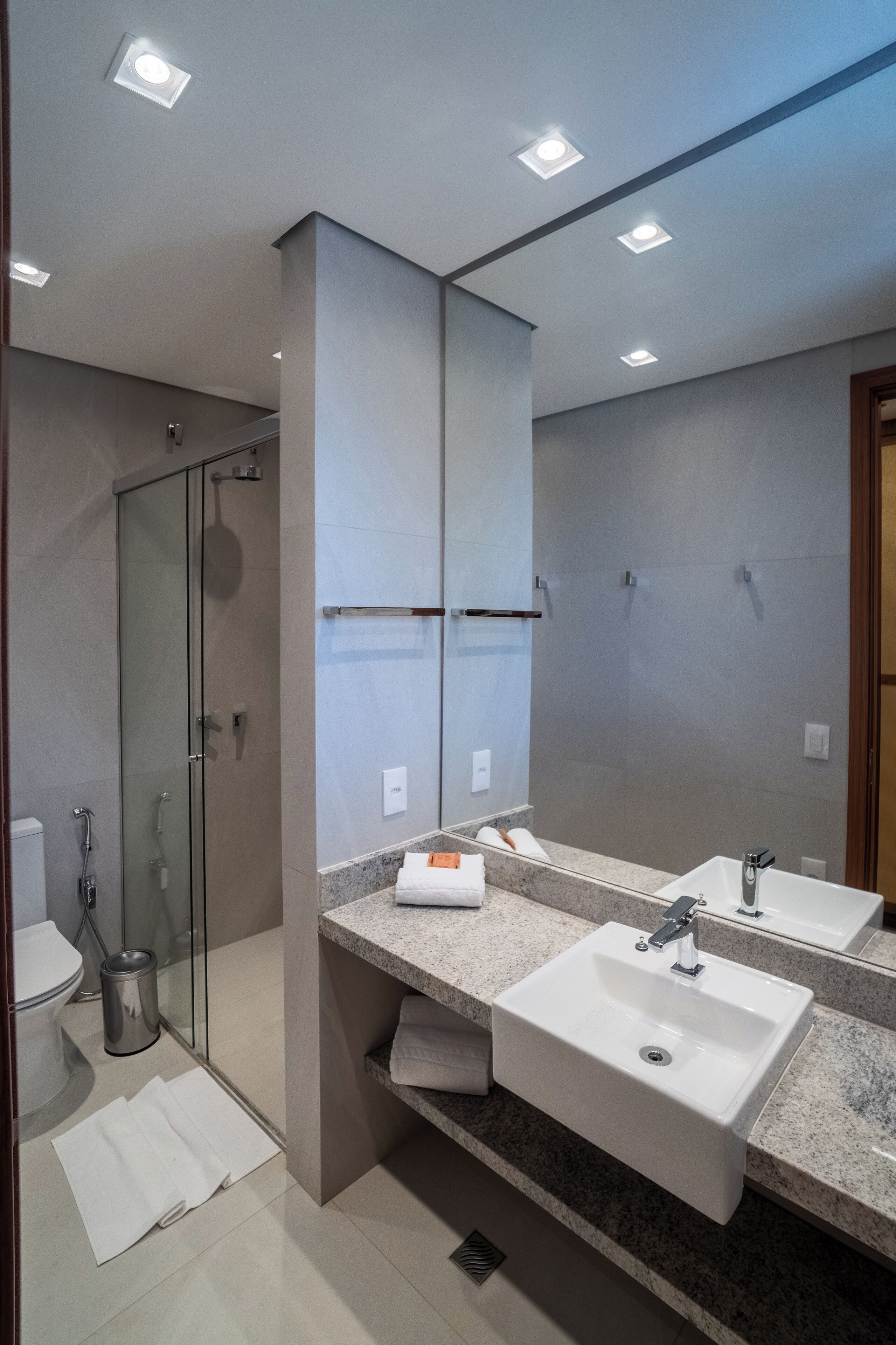 Un baño moderno con cabina de ducha de vidrio, dos lavamanos y un espejo grande.